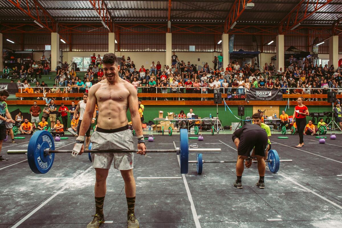 Atleta sonriendo junto a su barra tras completar un workout en competición