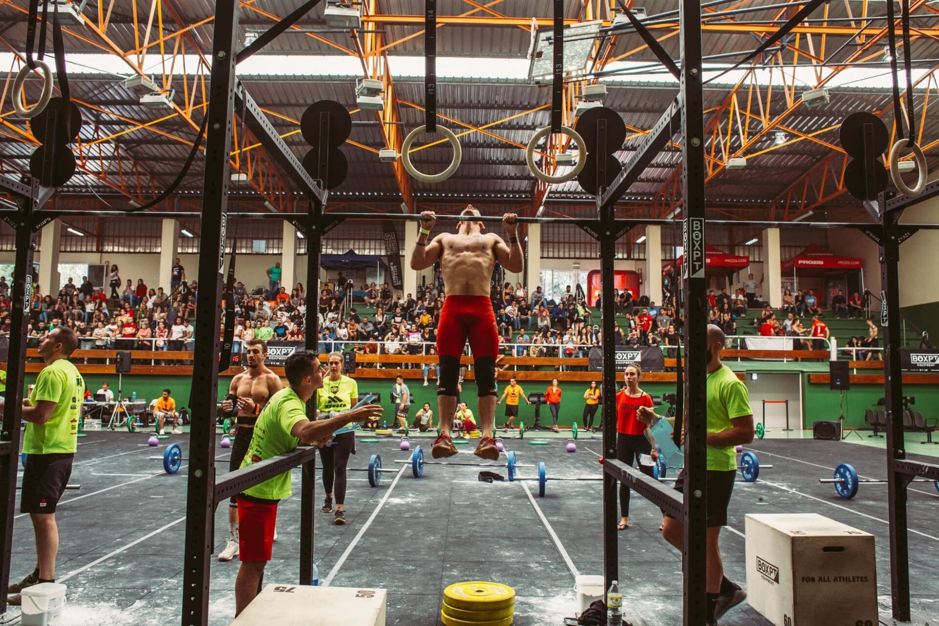Atleta haciendo dominadas en la final de una competición de CrossTraining, con jueces y grada llena